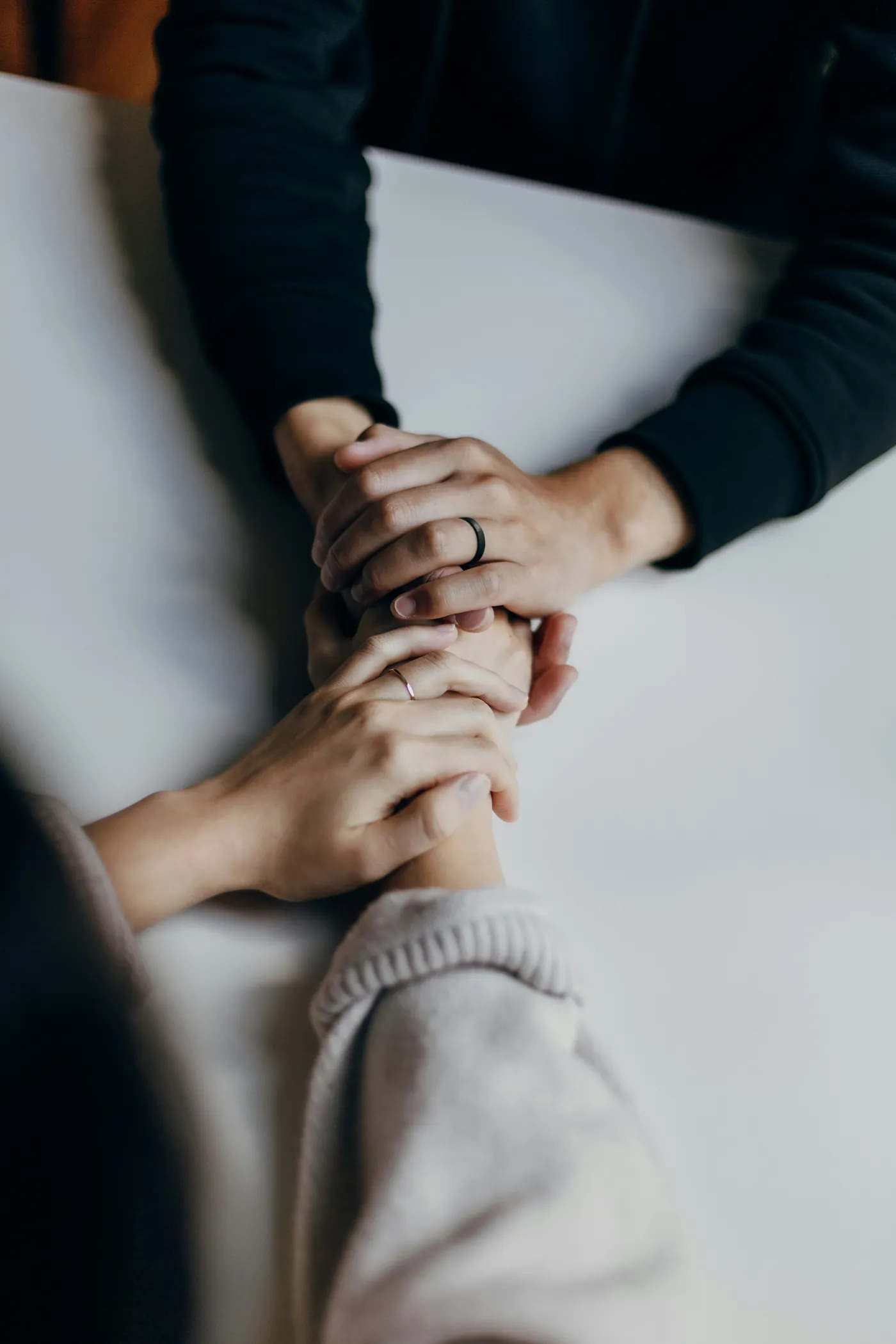 Two pairs of hands resting together on a table during a counseling session